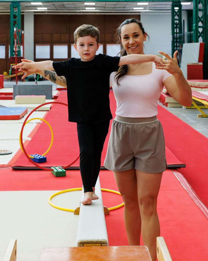 Sarah Granier accompagnant un jeune enfant sur une poutre basse