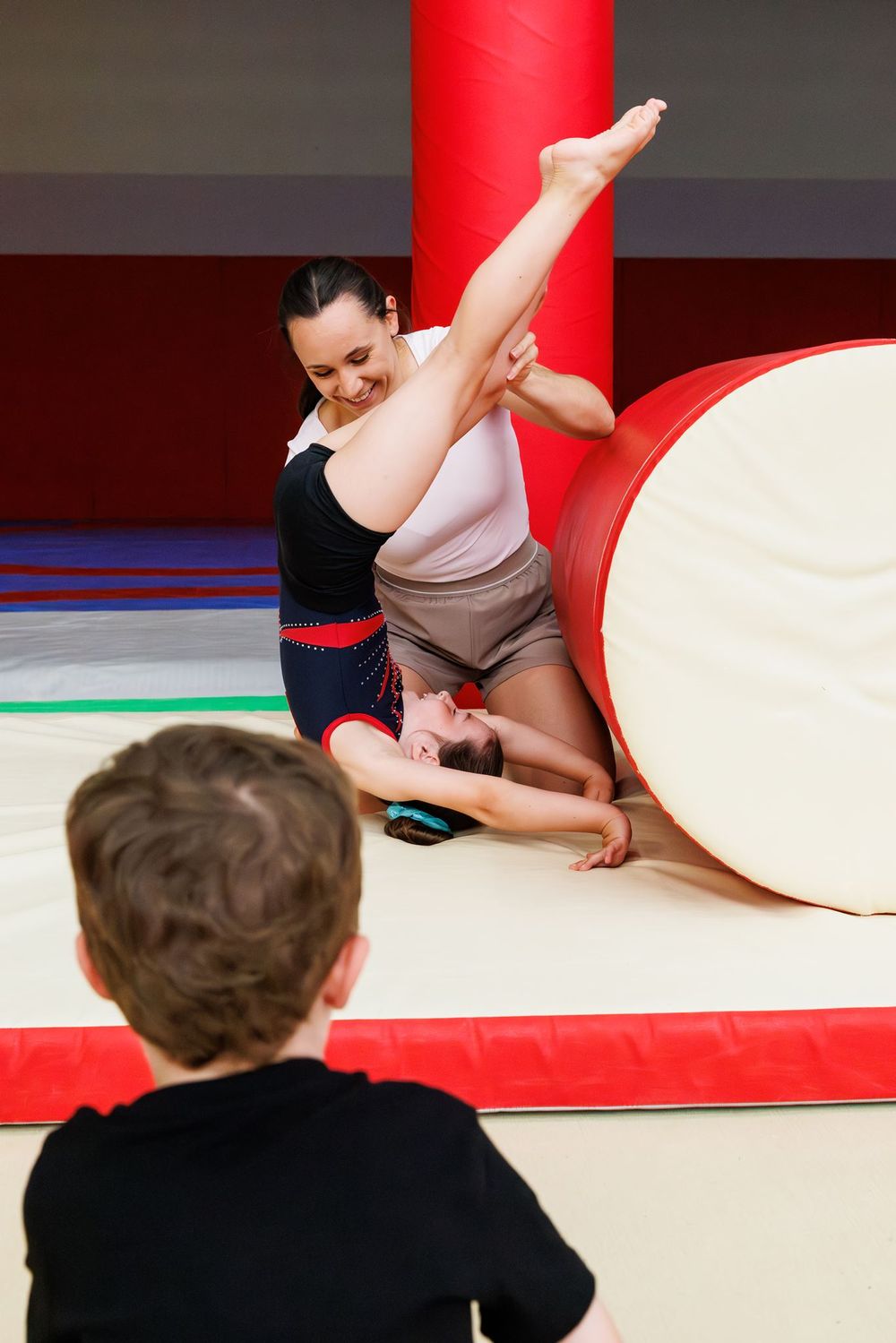 Sarah Granier aidant une jeune gymnaste en pont, devant un jeune public